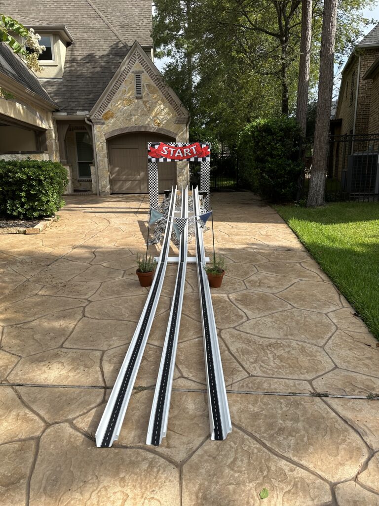 DIY vintage race car birthday party with handmade Pinewood Derby track and checkered flag starting archway