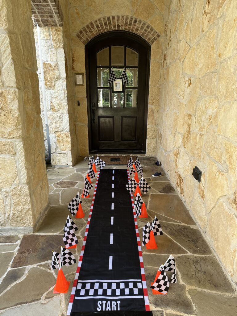Checkered race-track runner lined with cones and flags in a stone entryway.