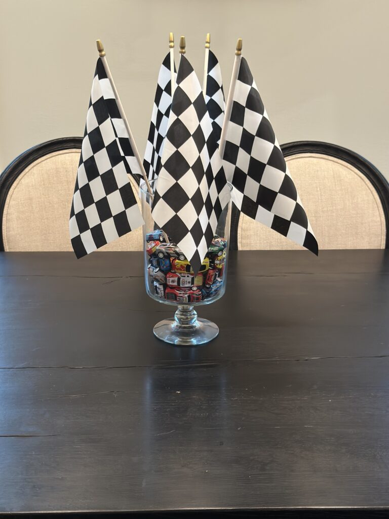 Pedestal glass filled with toy cars and topped with checkered flags.