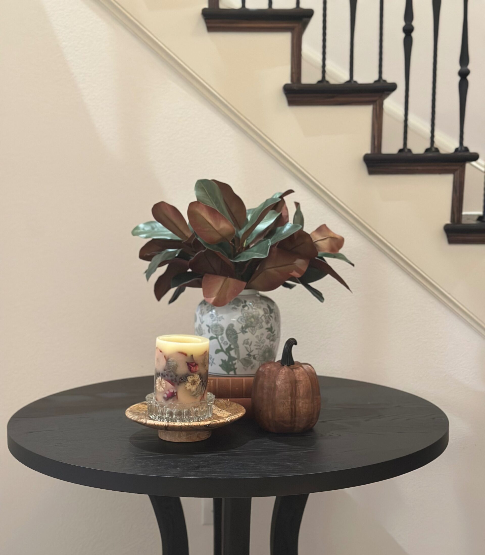 Fall entryway vignette with a floral ginger jar, spiced apple pillar candle, and wood pumpkin